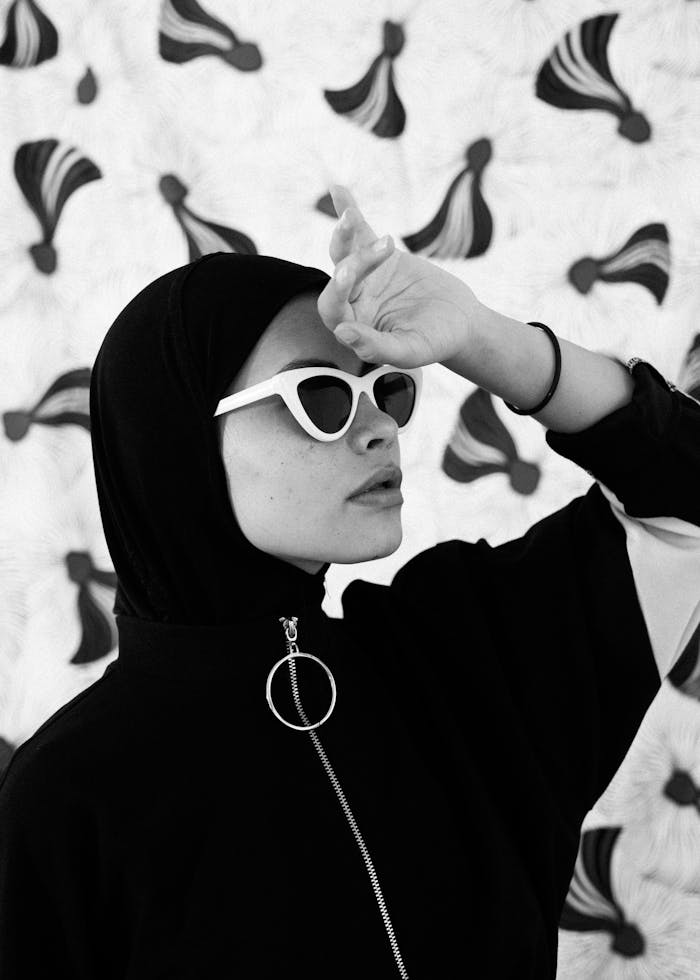 Black and white of young covered female touching head with hand and pensively looking away